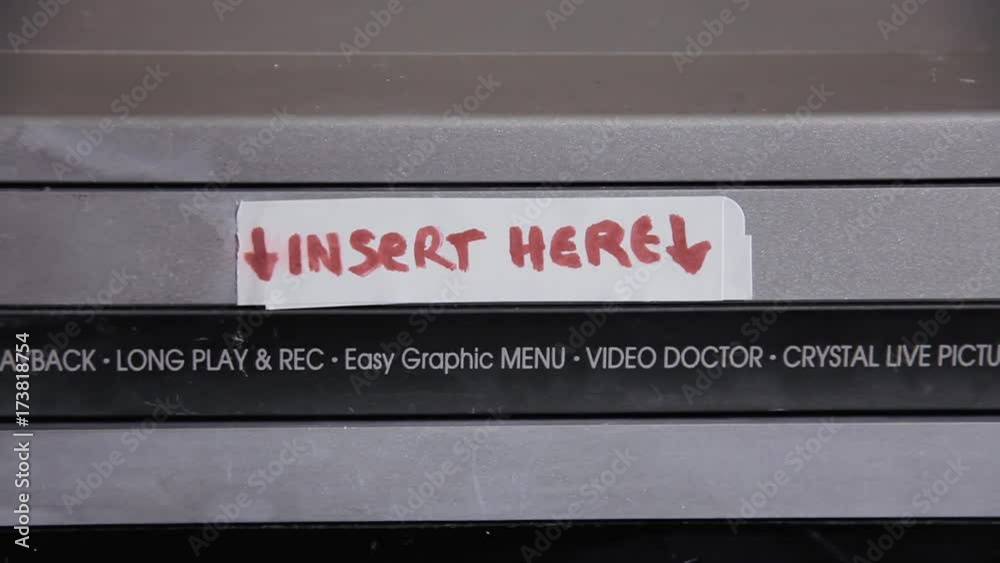Close-up: inserting and removing a VHS tape from a VCR. The title says Halloween.
Close-up: inserting and removing a VHS tape from a VCR. The title says Halloween.