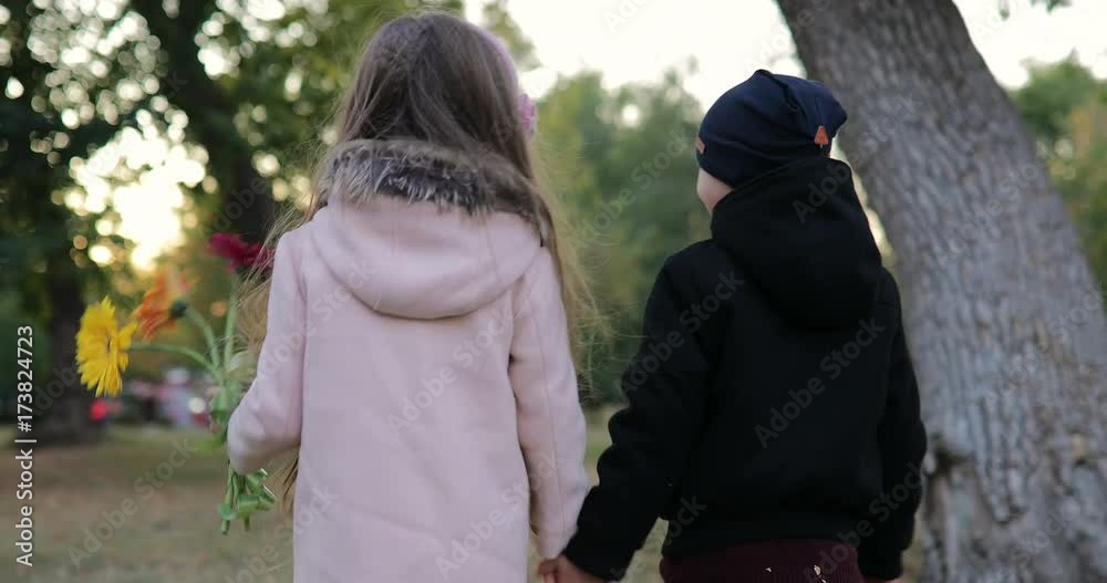 Two children walking in the park. A little boy and a little girl are talking and laughing Two children walking in the park. A little boy and a little girl are talking and laughing