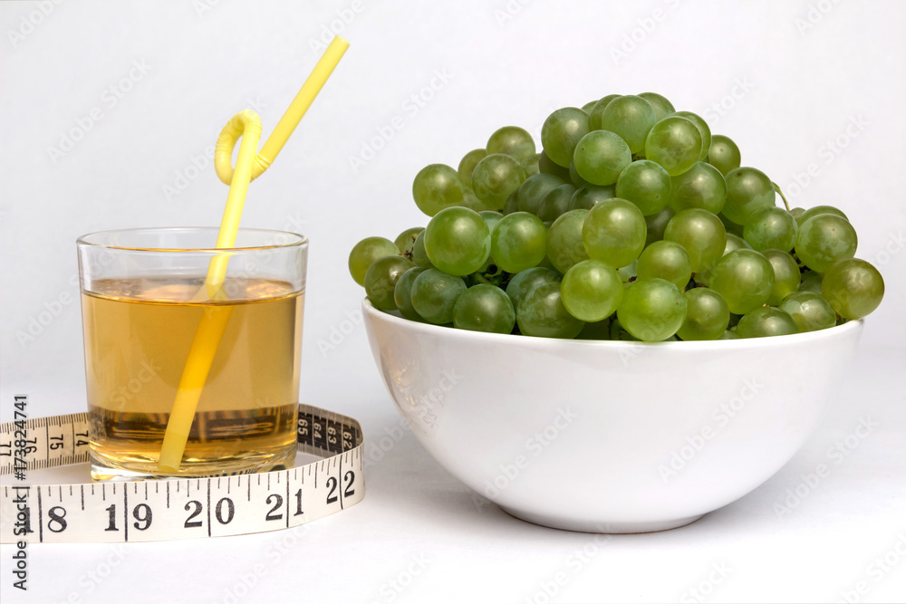 Full bowl of green grapes, a glass of grape juice with a straw and ...
