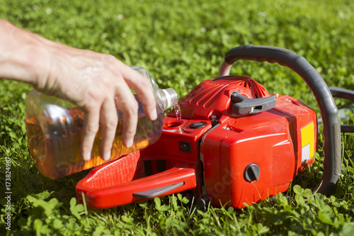 Handyman replenishes the oil in chainsaw for chain maintenance
