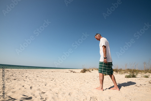 Man traveler, lost in thought, walks along the deserted seashore