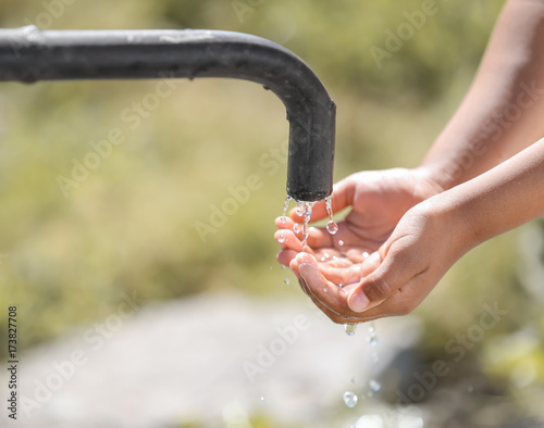 Billede på lærred African American child drinking water from tap outdoors