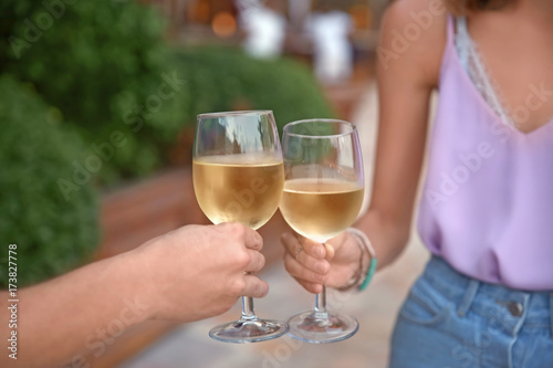 Man and woman holding glasses of white wine on blurred background