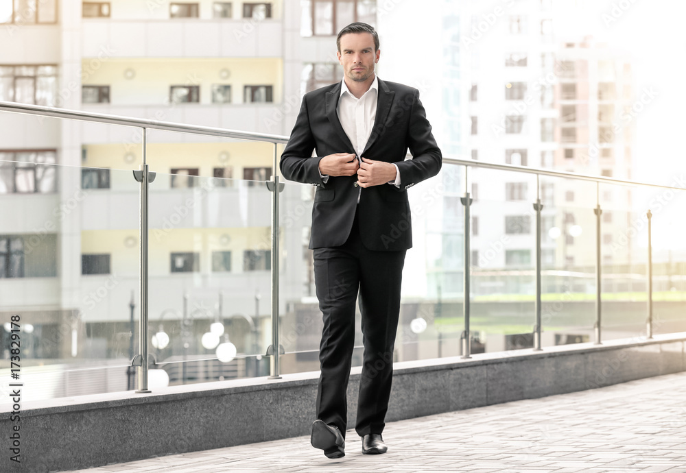 Handsome man in elegant black suit outdoors
