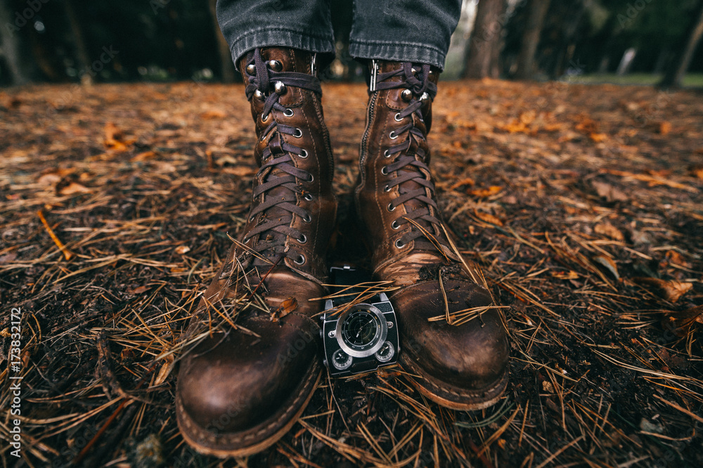 Rough distressed brown leataher handmade boots and watches on ground in  autumn forest with spruce needles, leaves and pine cones. Old vintage  hipster footwear. Masculine concept. Seasons and time. Stock-foto | Adobe