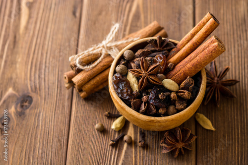 Set of spices for mulled wine in ceramic bowl on wooden table. © nesavinov