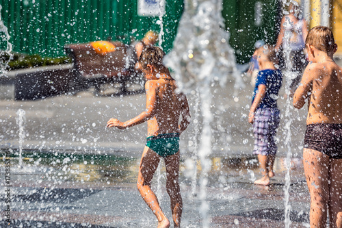 Cute little children playing with a city fountain on hot and sunny summer day at Kiev, Ukraine. photo