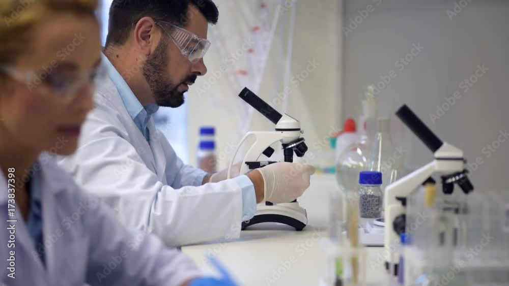 Male researcher looking through microscope in lab Male researcher looking through microscope in lab