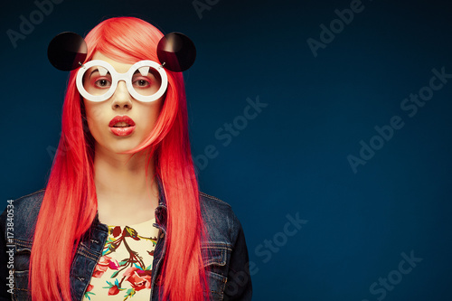 fashion girl with pink hair and big sunglasses over blue  background