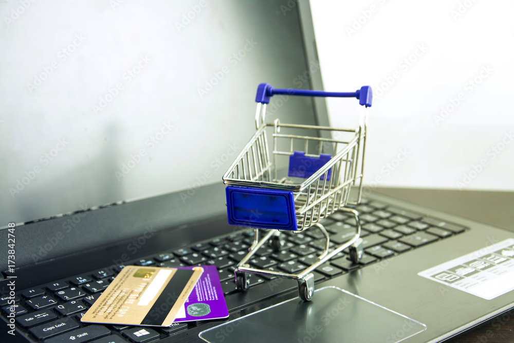 Computer notebook blank screen with shopping cart on wood table