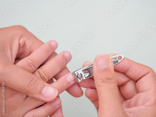 Family activity mother hand cut nails for kid by using nail clipper, with selective focus.