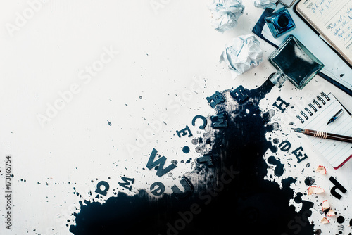 Header with spilled ink, crumpled paper, scattered letters, papers and notepads on a white wooden background. Creative writing concept. Flat lay with copy space. photo
