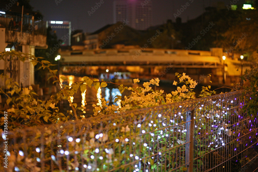Fairy lights illuminate a steel fence - Pretty evening scene beside the river in Malacca, the UNESCO world heritage site