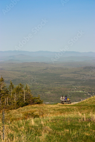 two hikers sitting on a picnic table with a great view