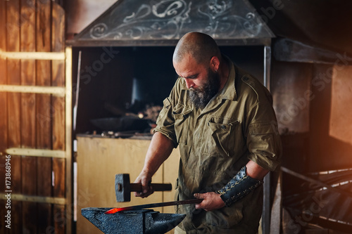 Blacksmith working in the forge. Manufacture of parts and weapons from molten metal, using the hammer and anvil.
