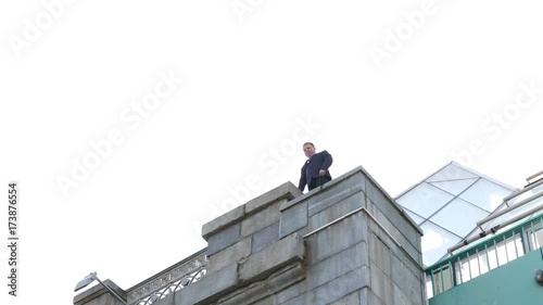 The man walks to the edge of the bridge and looks down. Shooting from the ground.