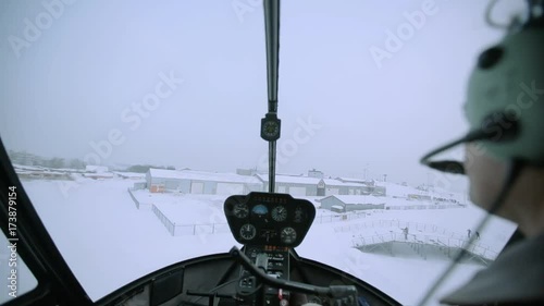 A red helicopter is flying over the snowy city.