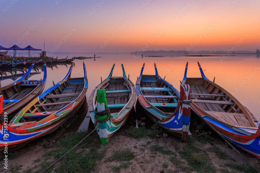 Traditional Painted Wooden Boats waiting tourists or passengers  on lake at sunrise or sunset in Mandalay at U-Bein Bridge, Amarapura, Mandalay, Myanmar (Burma)
