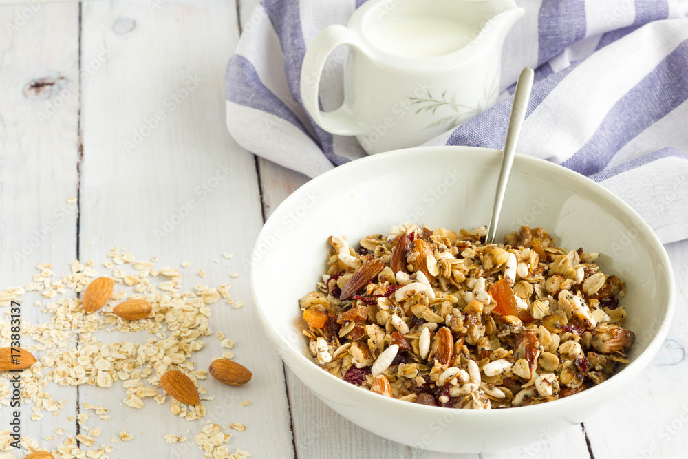 Homemade breakfast with oats, nuts and dried fruits. A cup of milk and blue table cloth in the background, natural colors. Homemade breakfast with oats, nuts and dried fruits. A cup of milk and blue table cloth in the background, natural colors.