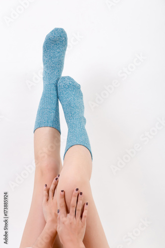 Closeup of the bare legs of a young woman wearing blue socks with his feet. Isolated on white background. Studio lighting
