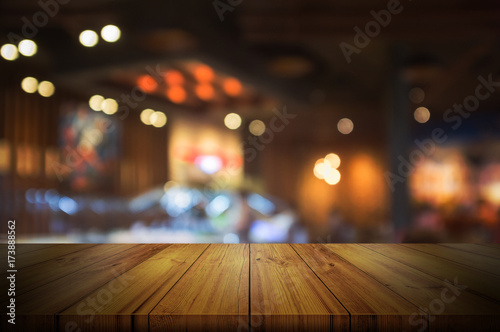 Empty wooden table top with blurred restaurant or cafe light background.