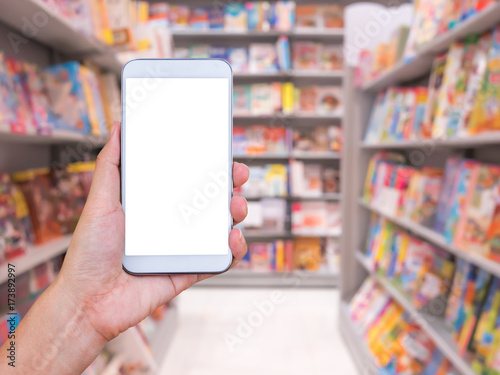 Hand holding smartphone with blur bookstore background.