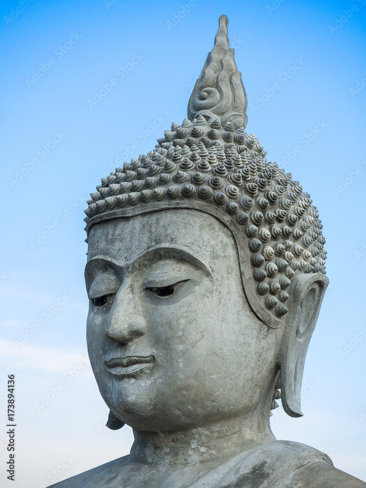 Close up face of Buddha statue with clear blue sky.