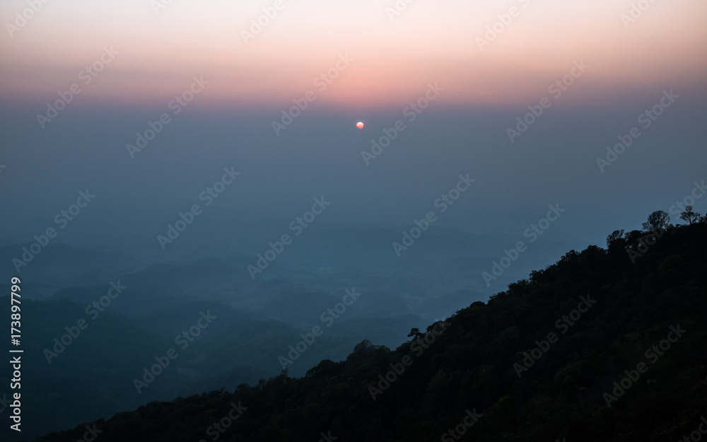 Fototapeta premium Sunset scene on hight mountain. Sunshine through the clouds. silhouette at the mountain.