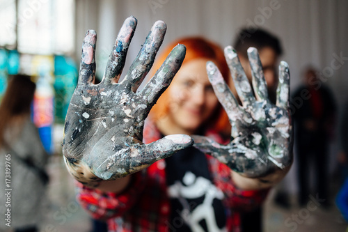 Papier peint Young person showing hands covered with paint during mass art therapy session