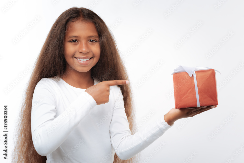 Charming girl pointing at gift box with finger Charming girl pointing at gift box with finger