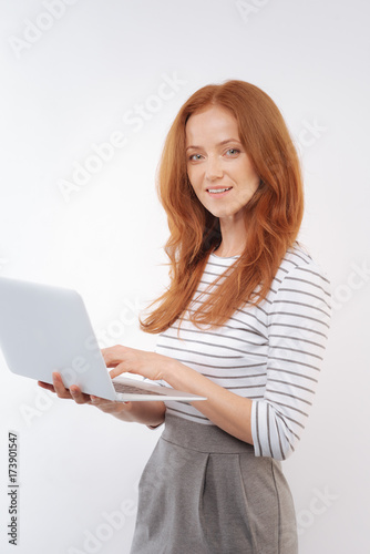 Charming red-haired woman posing with laptop