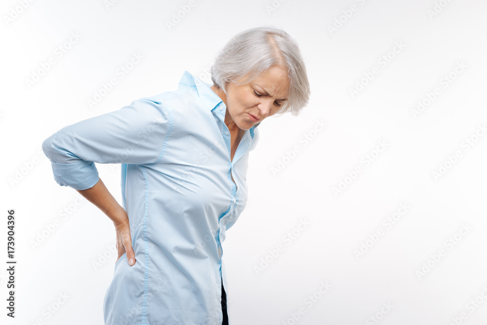 Grey-haired woman suffering from pain in lower back Grey-haired woman suffering from pain in lower back