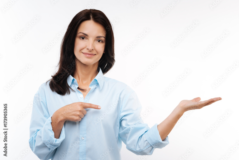 Pleasant woman stretching out hand and pointing at it