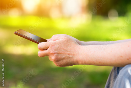 Female hands using mobile phone in park