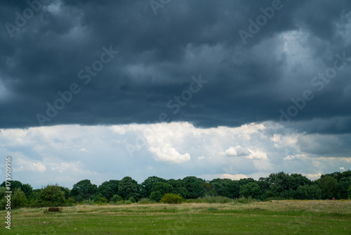 Dark storm clouds above horizon and green field © Brian Scantlebury