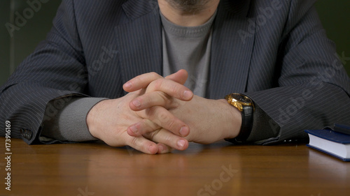 Businessman sitting with crossed fingers. Businessman sitting at the table with fingers crossed photo