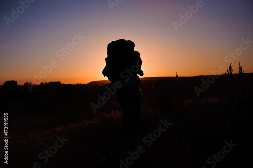 Young man is looking at sunset. Traveller with backpack.