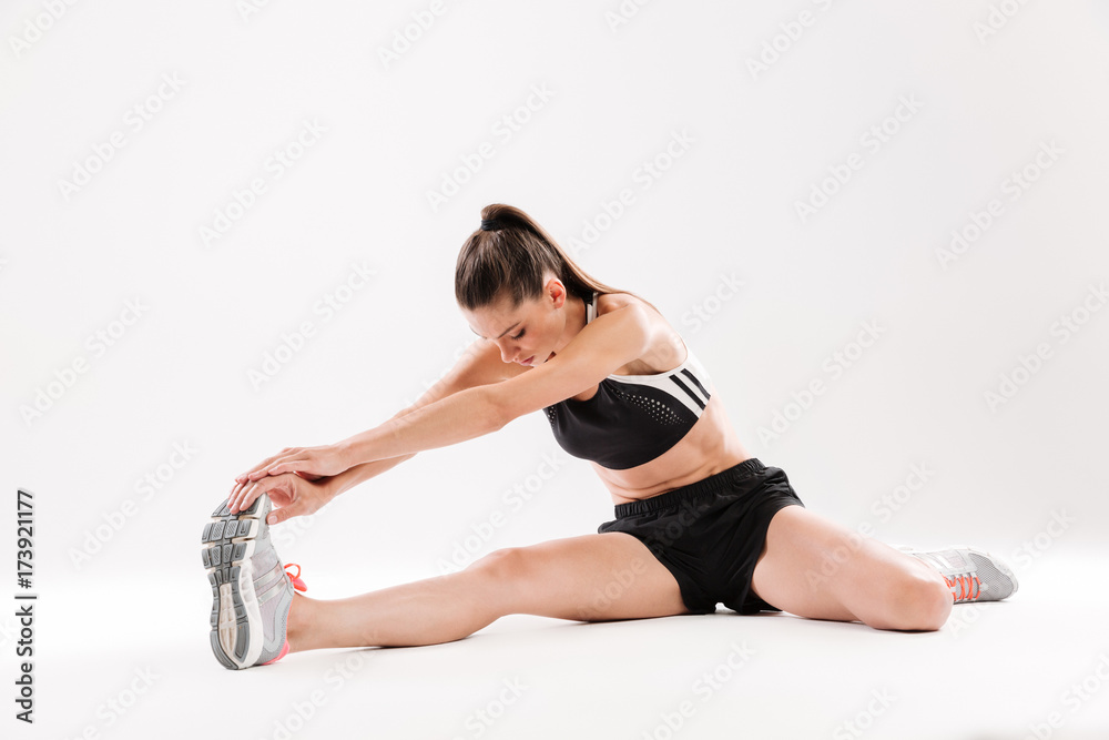 Full length portrait of a healthy motivated sportwoman stretching muscles Full length portrait of a healthy motivated sportwoman stretching muscles