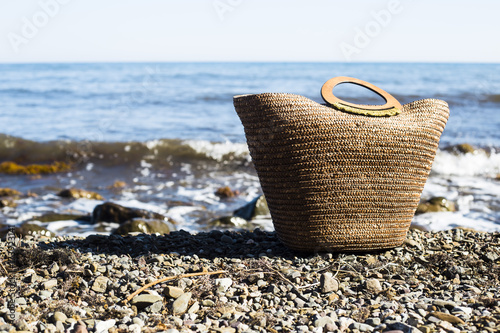 wicker basket bag with accessories for relaxation at sea stands on the coast with pebbles