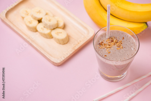Fresh made banana smoothie in a glass on pink background