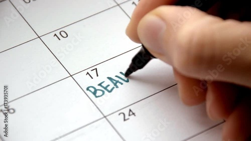 Writing BEAUTICIAN on calendar with a green marker