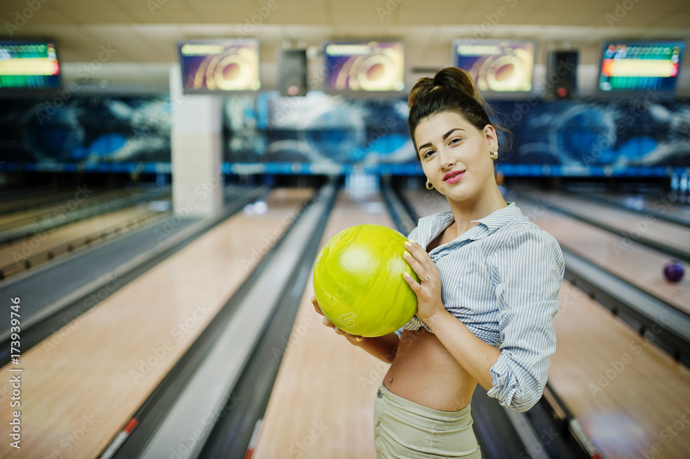 Fototapeta premium Girl with bowling ball on alley played at bowling club.