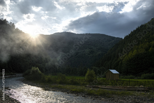 Scenic View Of The Vaser River With Mountains And Fog Against Grey Sky photo