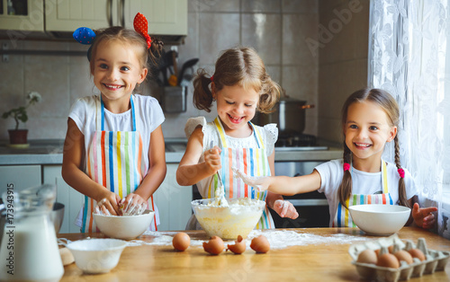 happy sisters children girls bake cookies, knead dough, play with flour and laugh