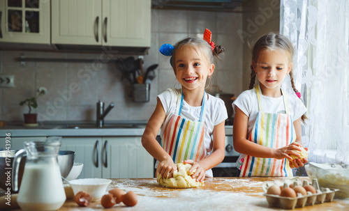 happy sisters children girls bake cookies  knead dough  play with flour and laugh