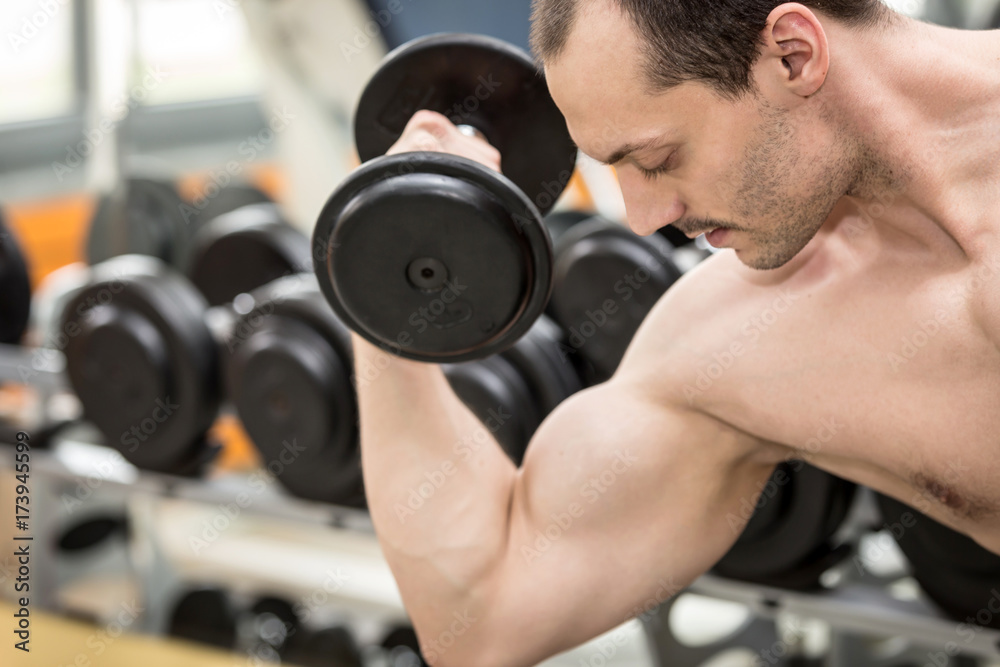 bodybuilder man doing biceps exercise with dumbbell in fitness club bodybuilder man doing biceps exercise with dumbbell in fitness club