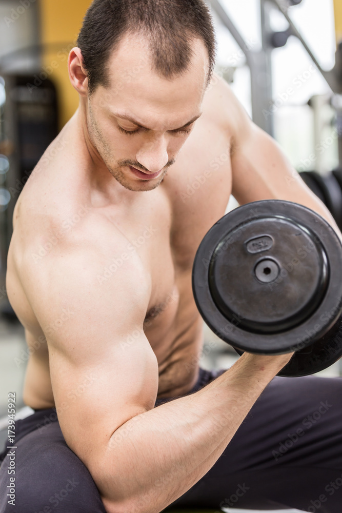 bodybuilder man doing biceps exercise with dumbbell in fitness club bodybuilder man doing biceps exercise with dumbbell in fitness club