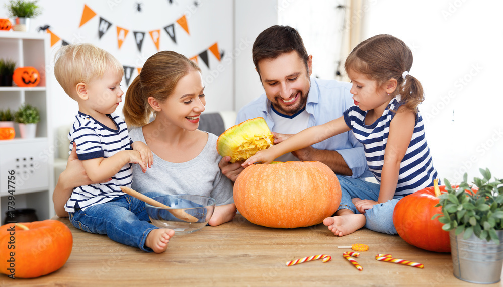 Fototapeta premium happy family mother father and children cut pumpkin for halloween