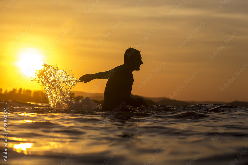 Surfer in ocean at sunset time