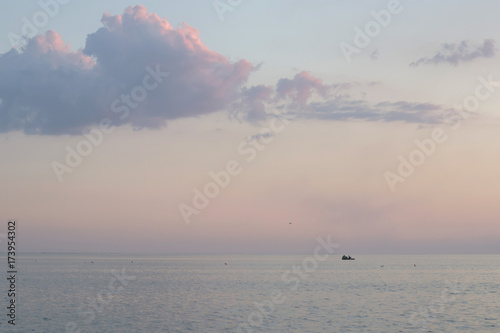 Quadro su tela Silhouette of an inflatable boat with fishers standing on a lake in a quiet nois